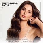 Kobieta z falującymi, lśniącymi włosami, podkreślająca zapach produktu. Tekst na obrazie wskazuje na połączenie kwiatowych i cytrusowych nut z wanilią.