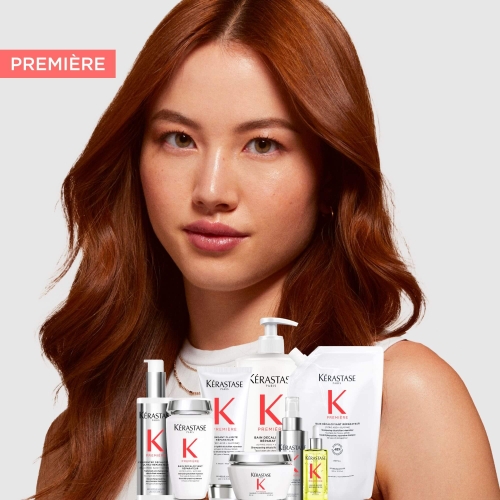 Kobieta z rudymi włosami na tle zestawu kosmetyków Kérastase Première
