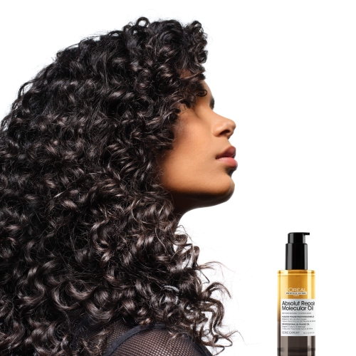 Kobieta z ciemnymi, sprężystymi lokami obok butelki olejku Absolut Repair Molecular.