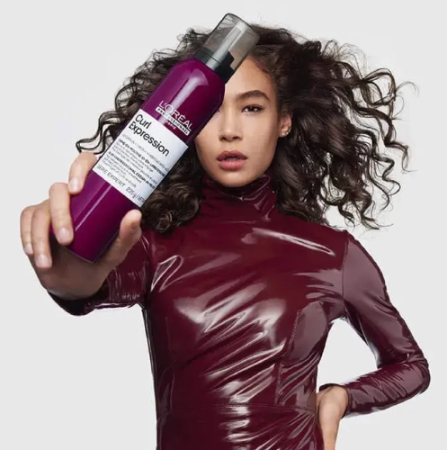 Modelka z kręconymi włosami trzymająca Piankę 10w1 L'Oréal Curl Expression