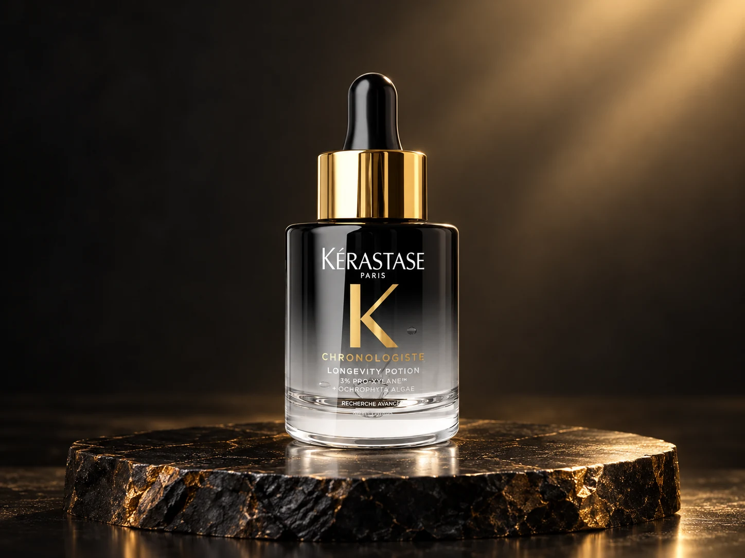 Czarno-przezroczysta butelka Kérastase Chronologiste Longevity Potion ze złotym kołnierzem i czarną pipetą na czarno-złotej podstawie.